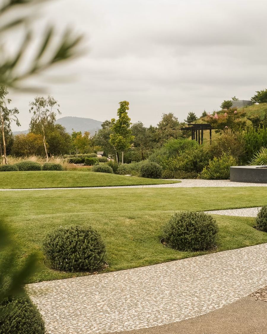 Broad manicured lawn with shaped shrubs and gravel paths at a commercial property