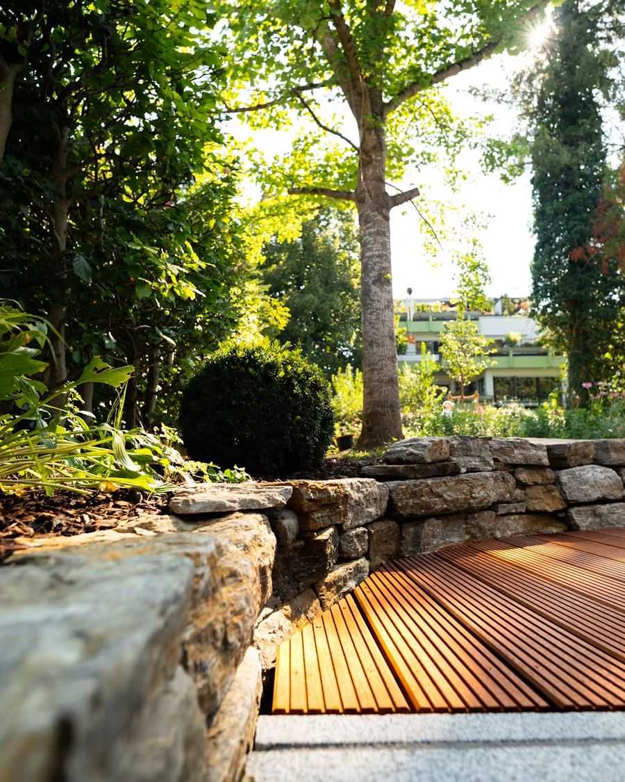 Weed-free mulched planting bed bordered by a stacked stone wall